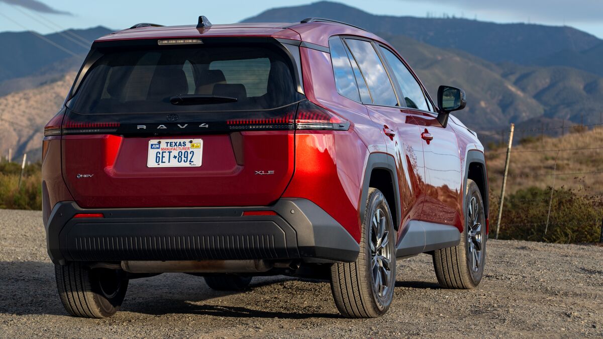 A rear left 3/4 angle photo of a 2026 Toyota Rav4 XLE against a hilly backdrop under blue skies.