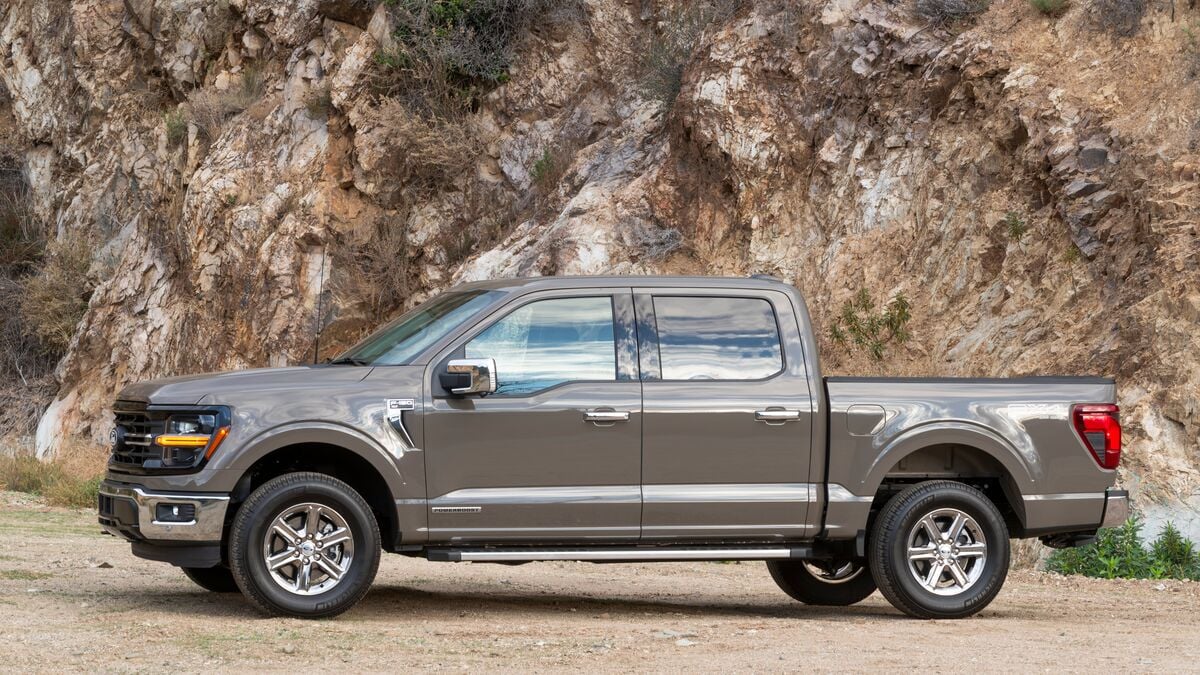 2026 Ford F-150 Hybrid XLT parked on dirt road near rocky outcropping.