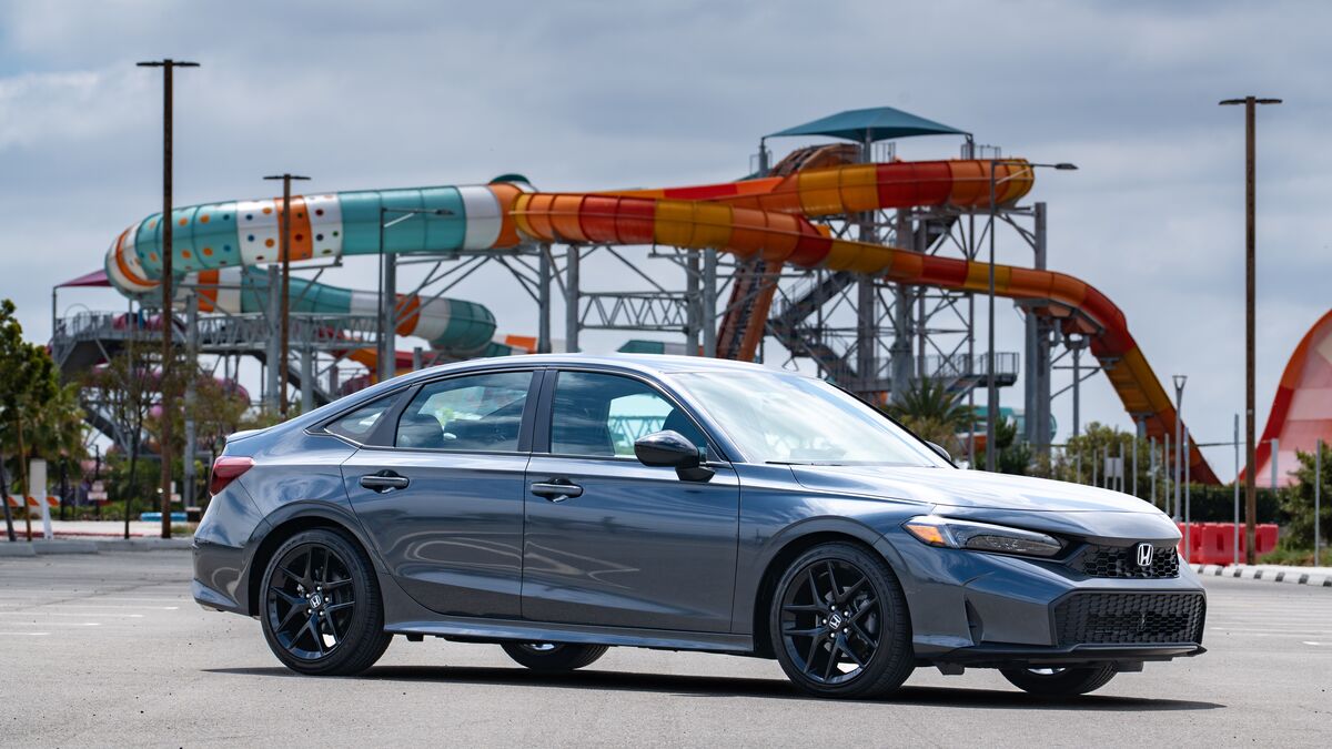 2026 Honda Civic Sport front right 3/4 view in a parking lot in front of a colorful water park slide.