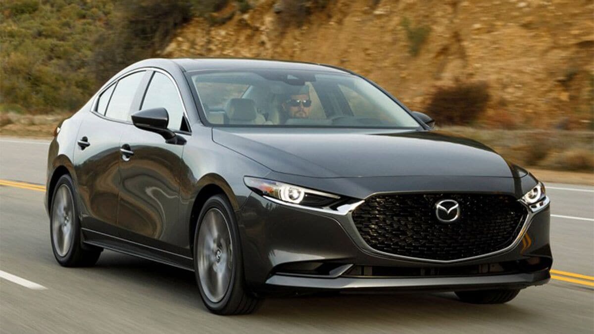 2021 Mazda3 in black driving down a road.