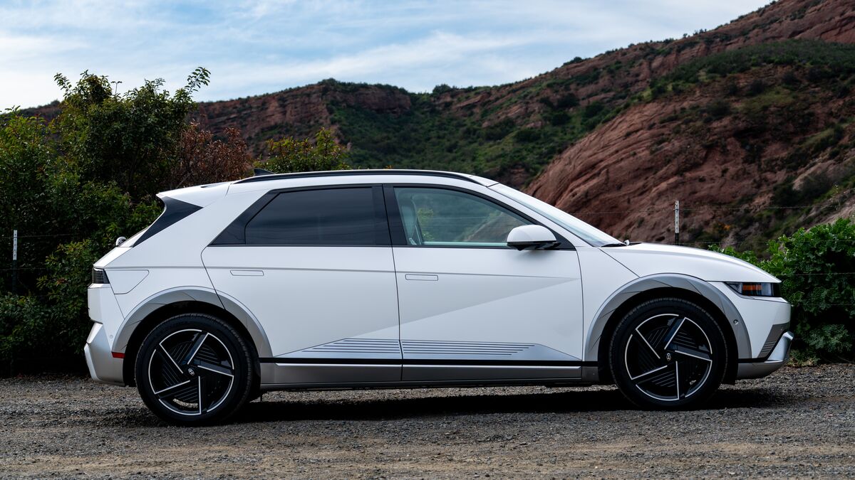 A right-side profile view of a 2026 Hyundai Ioniq 5 parked in the gravel with a red rock cliff in the background.