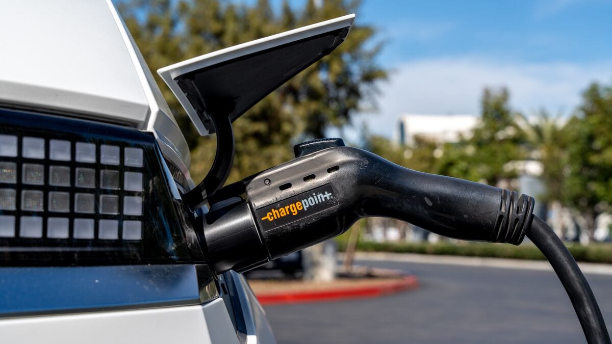 Detail photo of a Hyundai Ioniq 5 plugged into a Charge Point charger plug in a parking lot seen from the rear