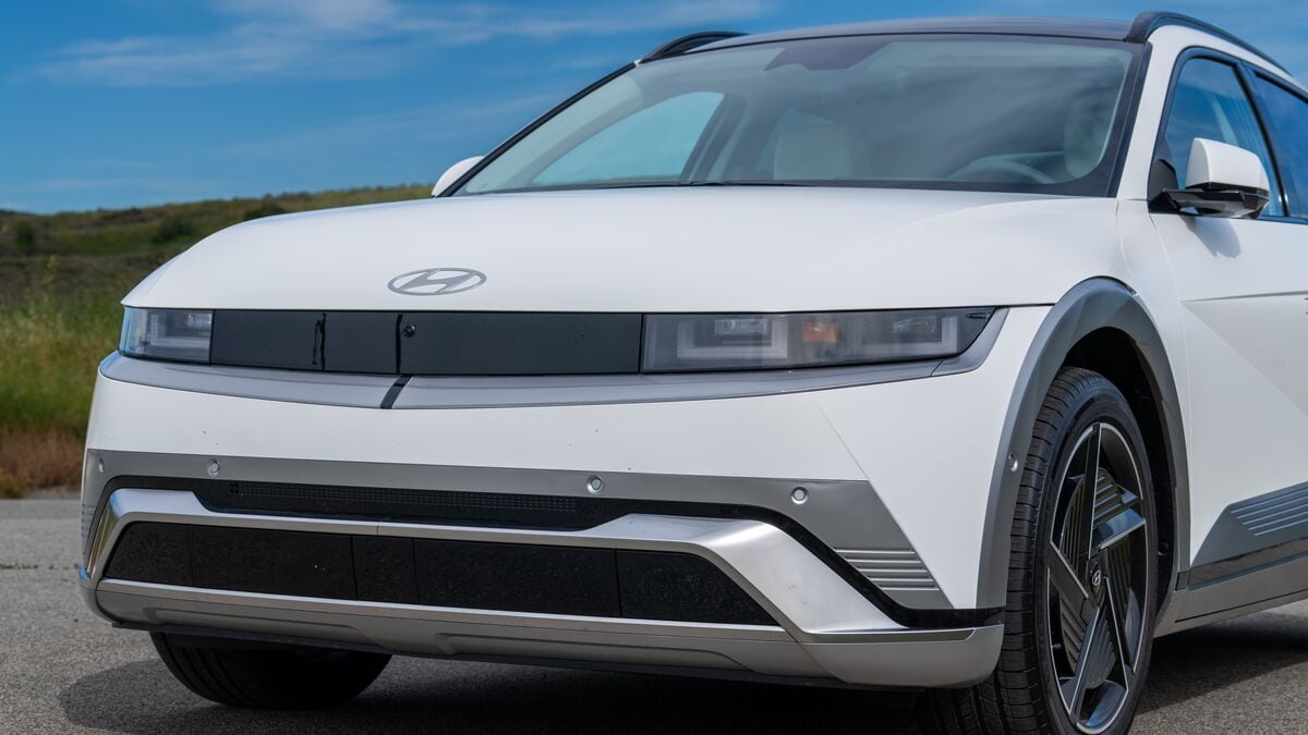 Hyundai Ioniq 5 tight front left 3/4 view against a hilly backdrop with blue skies and light clouds