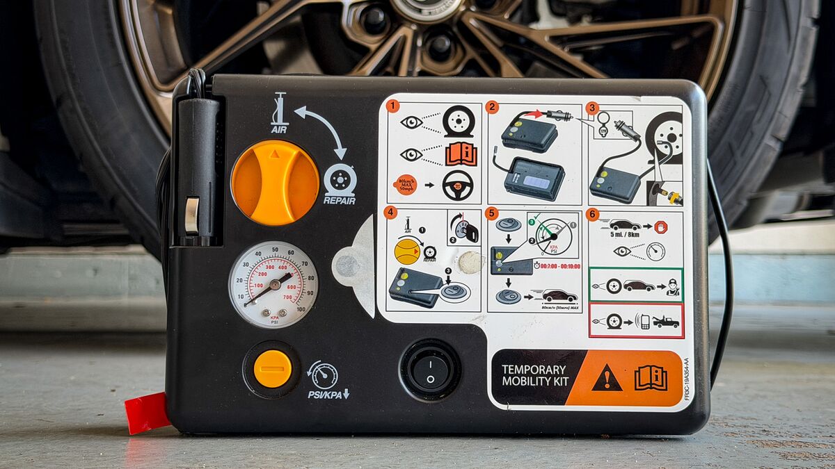 An air compressor and tire inflator kit next to a car tire.