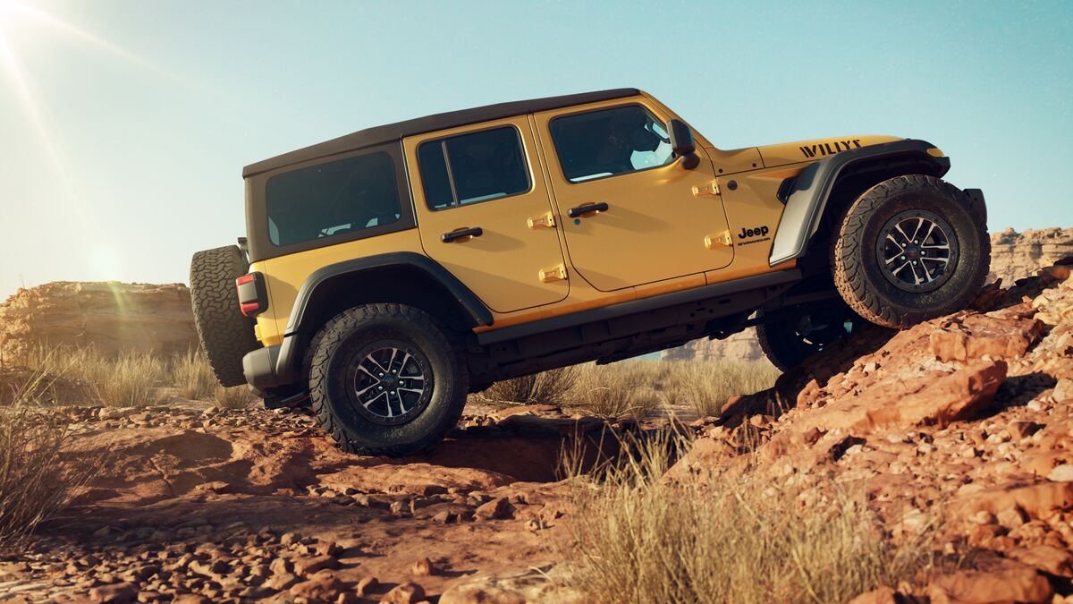 2026 Limited Edition golden yellow Jeep Wrangler Willys off-roading as seen from passenger side.