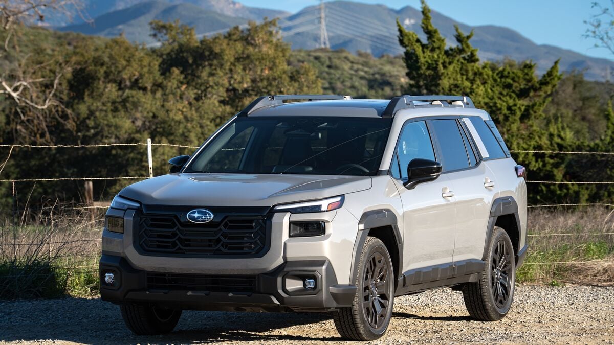 2026 Subaru Outback Wilderness front 3/4 left side against a green hillside and blue sky background