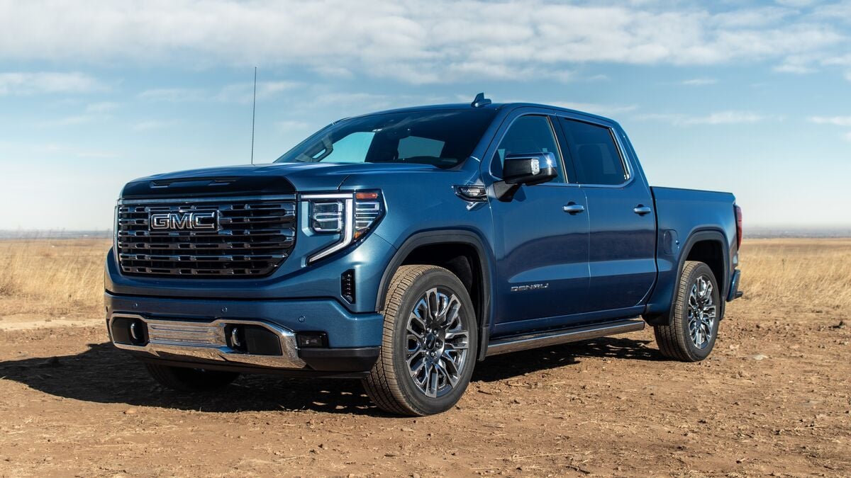 GMC Sierra 1500 front 3 quarter angle driver side parked on dirt with grassy background.