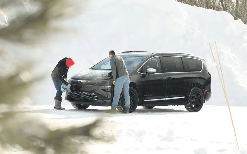 2027 Chrysler Pacifica parked in snow with 2 people around it.