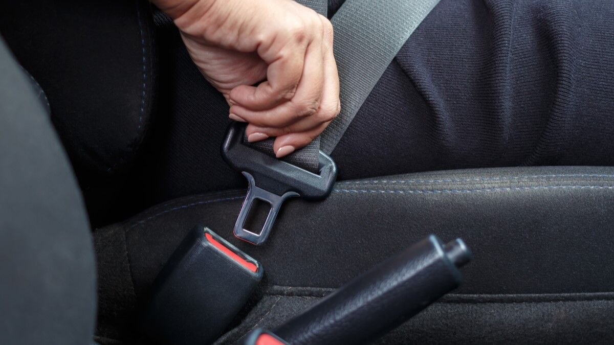A driver's hand fastens a seatbelt