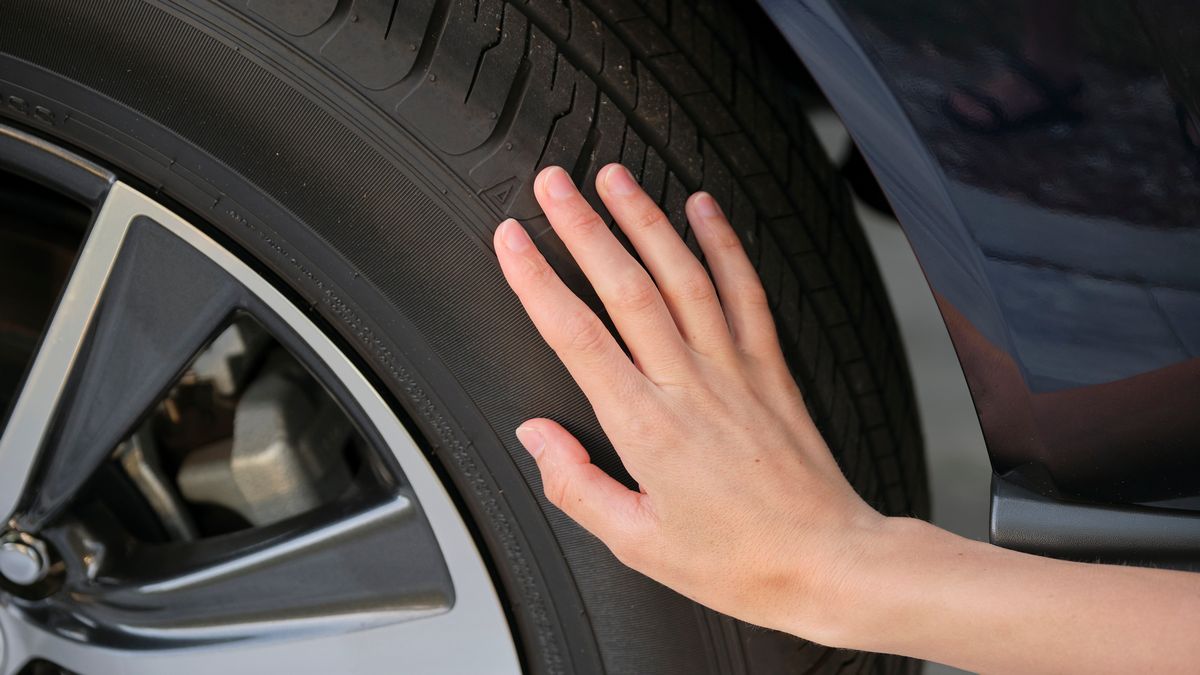 Female driver hand inspecting wheel tire of her new car.