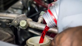 A technician pouring transmission fluid.