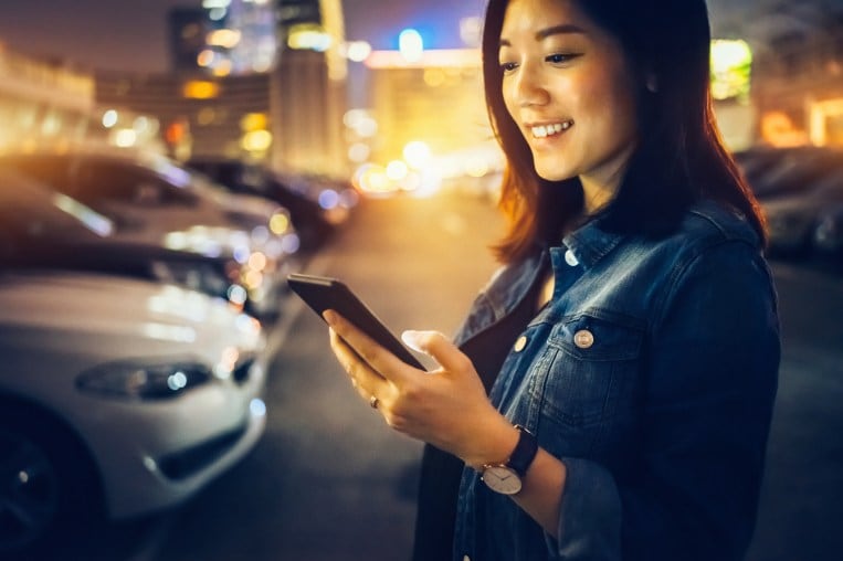 Cheerful Young Asian Woman Text Messaging On Mobile Phone In The City At Night