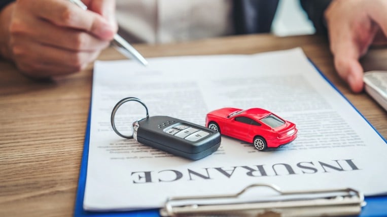 Keys and toy red car on an insurance policy