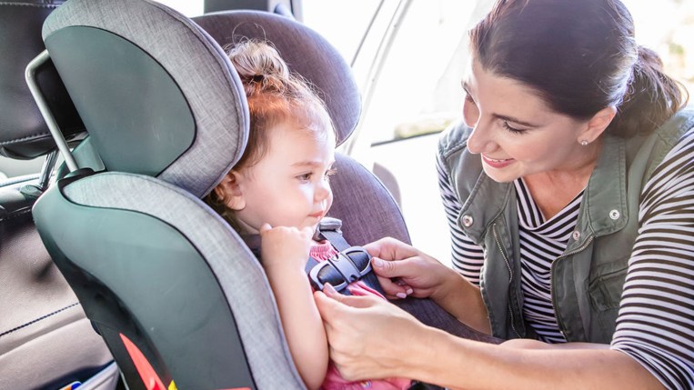 Mother buckling child into car seat
