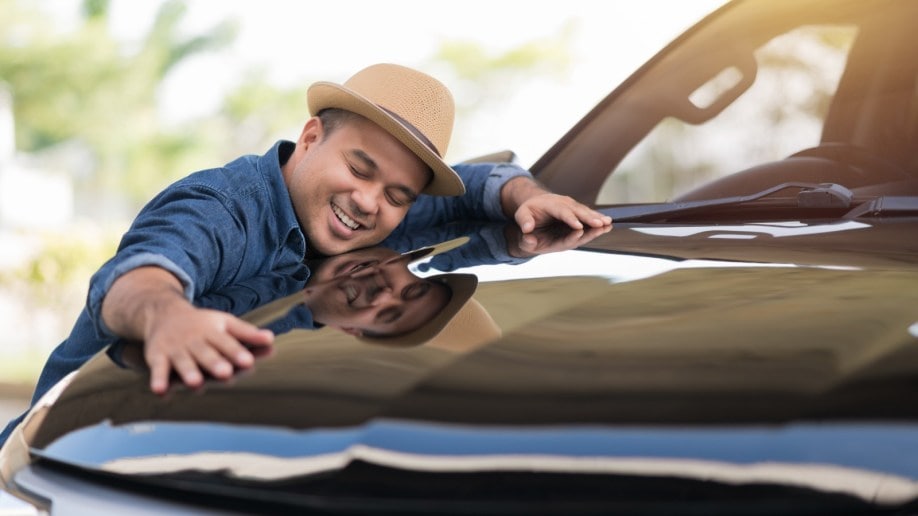 Person hugging a car after paying cash for its ownership