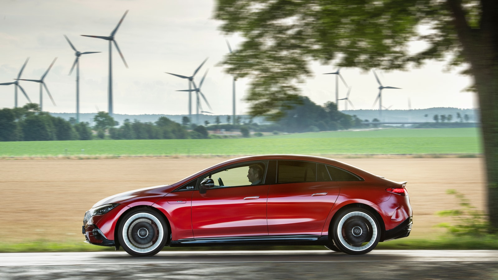 2023 Mercedes-AMG EQE red sedan near wind turbines