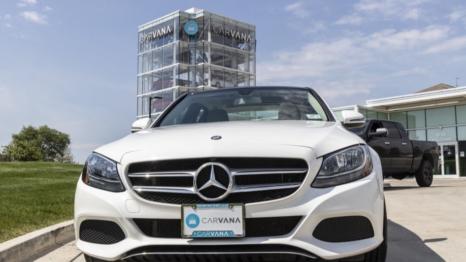 A used Mercedes parked in front of a Carvana "car vending machine" tower.