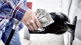 A customer refills gas in a car while holding money