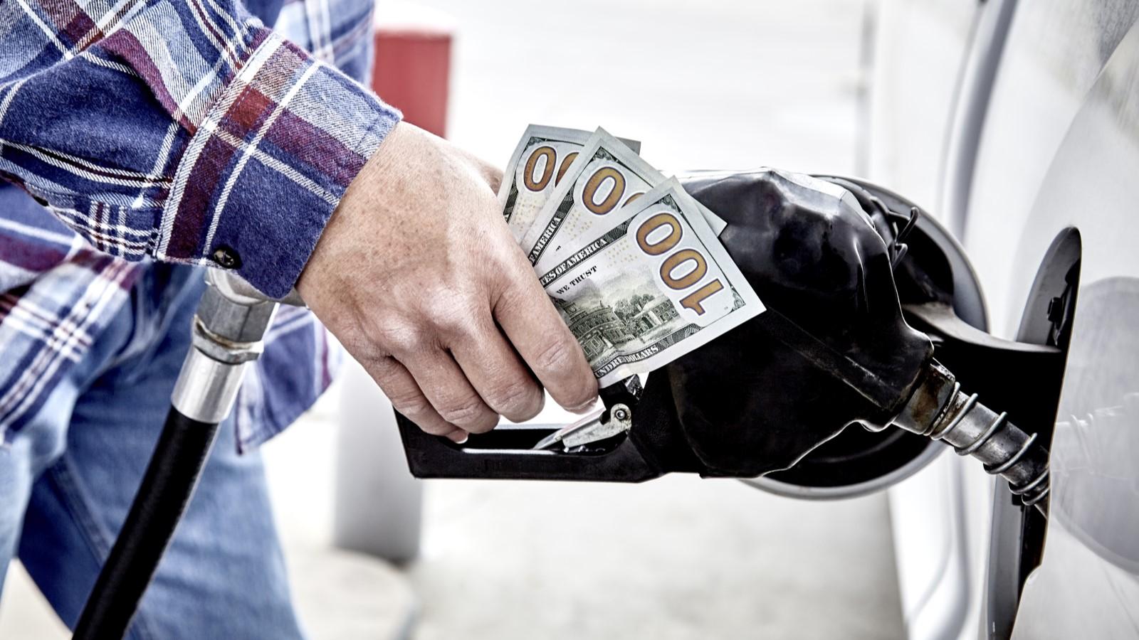 A customer refills gas in a car while holding money