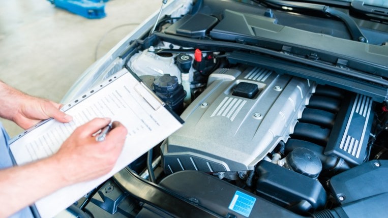 Mechanic with checklist including car air conditioning