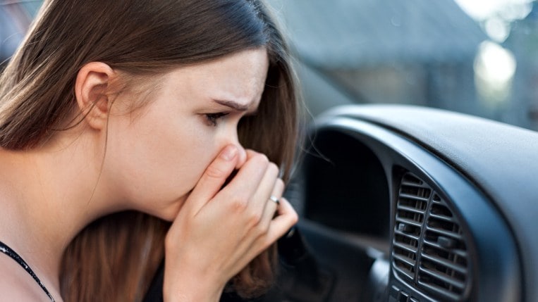 Woman smelling odor in air conditioning vent