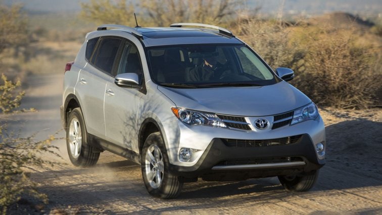 2013 Toyota RAV4 in silver driving down a dirt road.