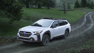 White 2023 Subaru Outback driving on dirt road