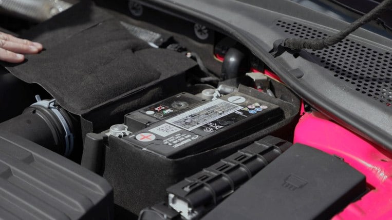Preparing to connect jumper cables to a car battery's positive and negative terminals.