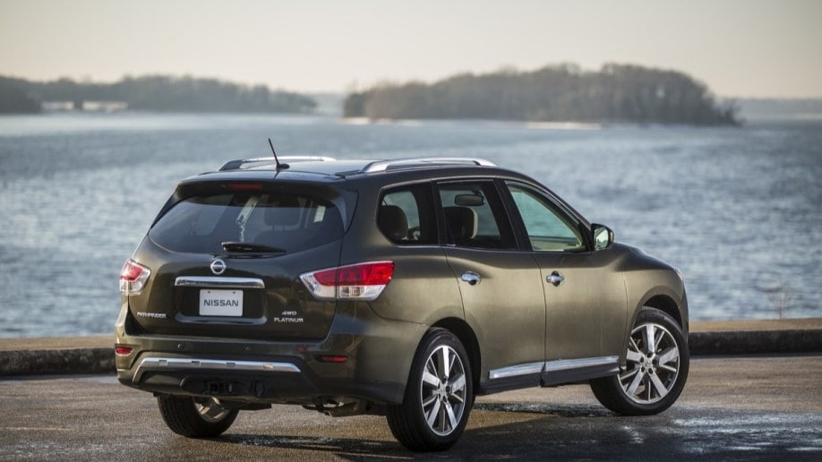 A grey 2016 Nissan Pathfinder is parked before a still body of water. We see the SUV from a rear three-quarter angle.