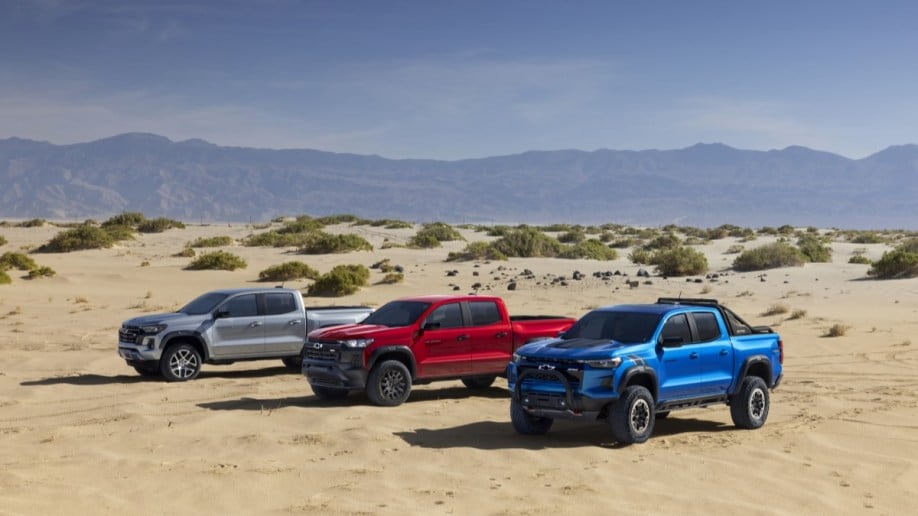 Three varieties of Chevy Colorado sit parked in the desert -- a silver LT, red Trail Boss, and blue ZR2.