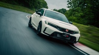 The 2023 Honda Civic Type R drives on a test track. The car is white. We see it from a low angle, facing slightly to our right.