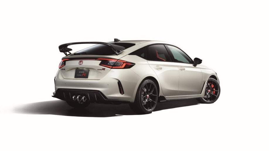 The 2023 Honda Civic Type R sits against a white background. We see it from a rear quarter angle, facing to our right. The car is white, with a high rear wing sitting on die-cast aluminum struts.