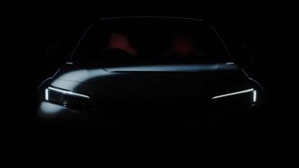 A teaser image Honda has released to whet appetites for the 2023 Civic Type R. It shows the front of the car in heavy shadow. We can tell that it is painted white, with seats upholstered in red.