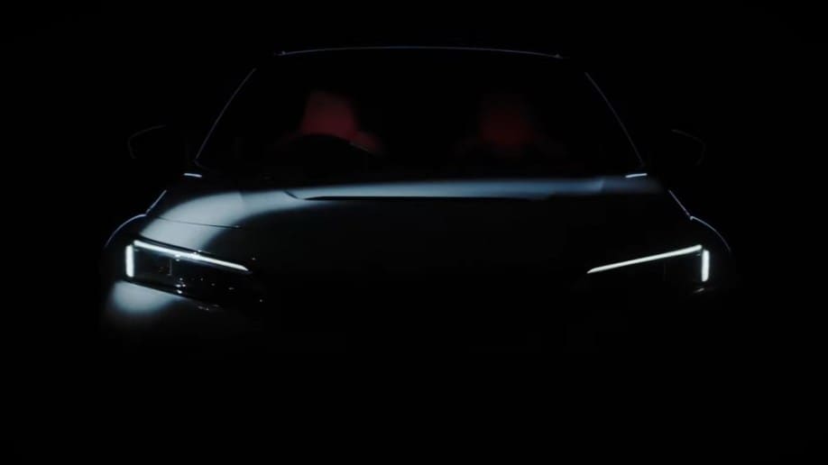A teaser image Honda has released to whet appetites for the 2023 Civic Type R. It shows the front of the car in heavy shadow. We can tell that it is painted white, with seats upholstered in red.