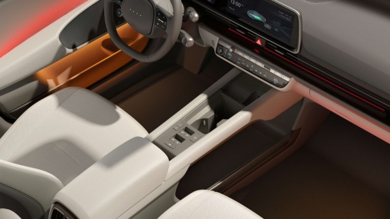 The cabin of the 2023 Hyundai Ioniq 6, seen from above. The ambient lighting is now set to orange below the arm rest, and red above.