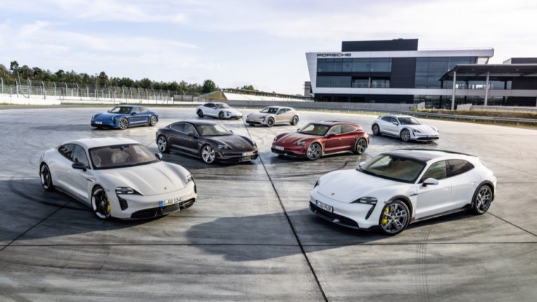 The full lineup of 2023 Porsche Taycan electric vehicles sits parked together. They include sedans, Sport Turismo wagons, and Cross Turismo lifted wagons in a rainbow of colors.