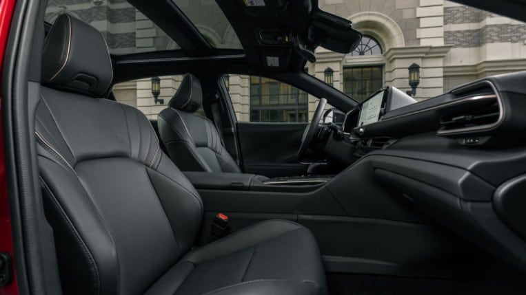 The interior of the 2023 Toyota Crown. It is upholstered in black SofTex, a leather-like material. The transmission tunnel dividing driver from front passenger is tall, creating a deep bathtub feel for both.