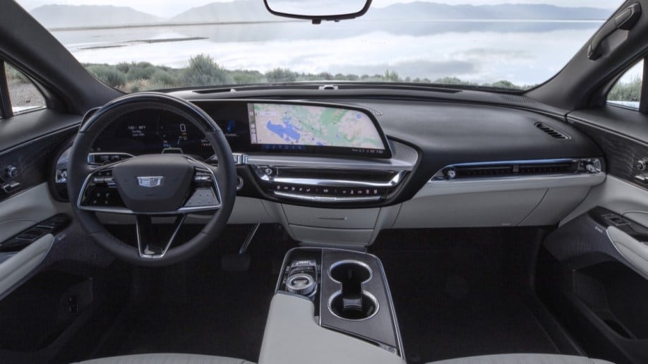 The interior of the 2024 Cadillac Lyriq. It is gray and cream colored, with a large central touchscreen and glossy black trim.