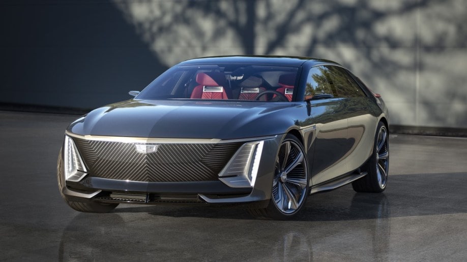 The Cadillac Celestic show car sits parked on a glossy concrete surface. The car is a glossy medium gray, with a black false grille with dozens of thin LED lines. We see it from a front quarter angle, facing slightly to our left.