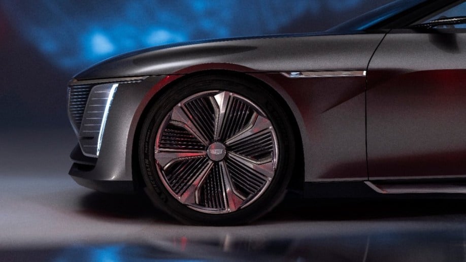 A teaser photo shows the front quarter of the Cadillac Celestiq show car. It is gunmetal gray, with a blunt nose and a crystal inset of a winged figure behind the front fender.