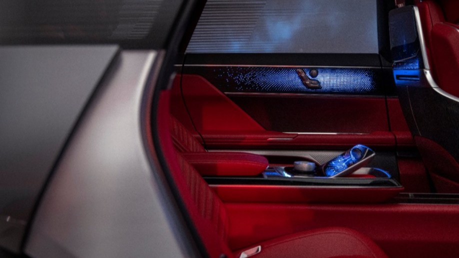 A teaser photo shows the rear seats of the Cadillac Celestiq show car. They are upholstered in blood red leather, with blue lighting accents and a touchscreen console between them.