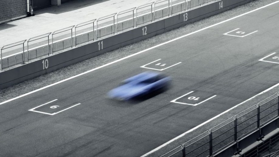 A deliberately blurred photo of a hatchback on a race track. We see the car from overhead. It appears in a shade of light blue Hyundai often uses to market its high-performance vehicles.