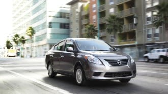 A 2012 Nissan Versa sedan in grey, seen from a front quarter angle