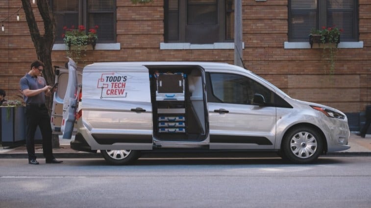 The 2021 Ford Transit Connect van in profile. We see it with both the rear and sliding side doors open.