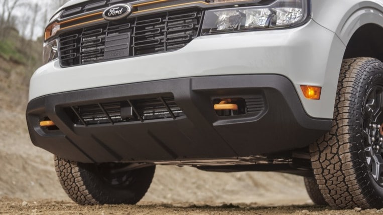 A closeup of the grille of the Ford Maverick Tremor, showing its bright orange tow hooks.