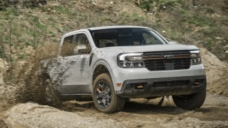 The Ford Maverick Tremor blasts through mud. We see the truck from a front quarter angle, headed slightly toward our right. It is tossing mud off its back tires.