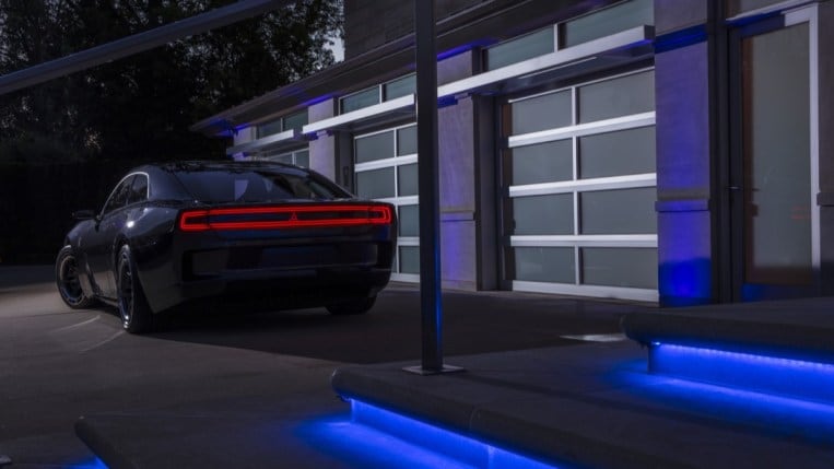 The Dodge Charger Daytona SRT Concept from a rear angle with its lights on