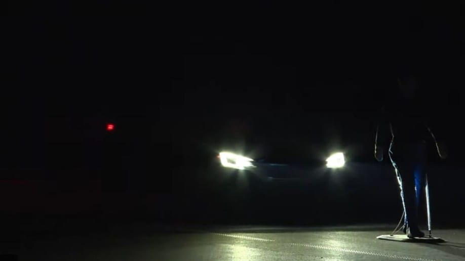 A car stops just short of hitting a mannequin during IIHS nighttime testing of automatic emergency braking systems