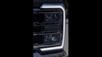 A teaser image showing the headlights of the 2023 Ford Super Duty truck