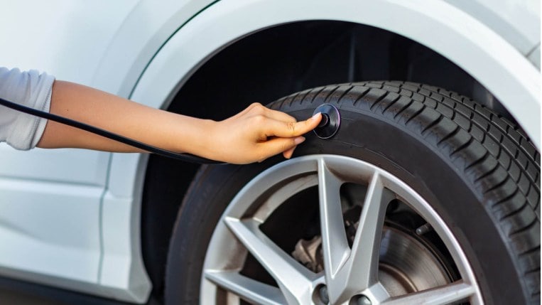 A person holding a stethoscope to a car tire.